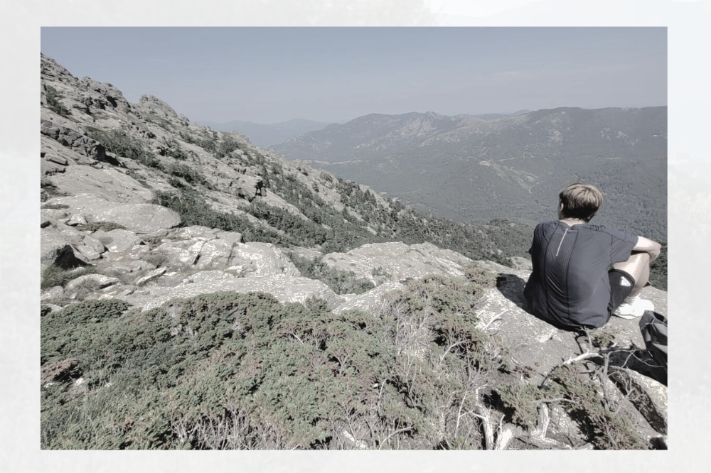 Person sitting on a rock with mountains in the background, text about Atmos' origins.